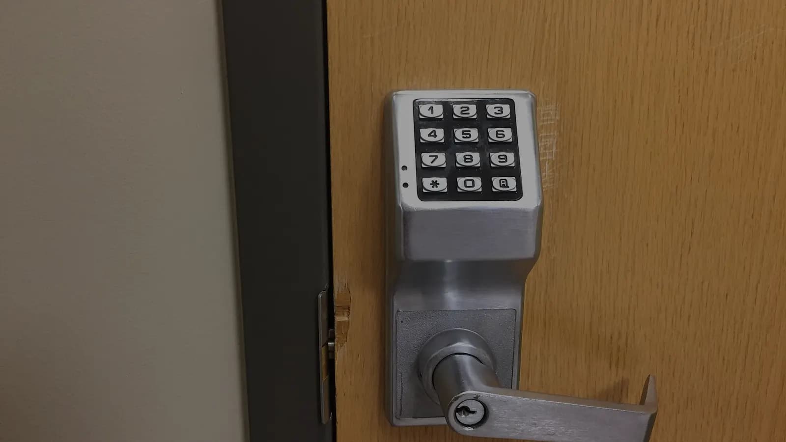 A keypad door lock with a lever handle on a wooden door