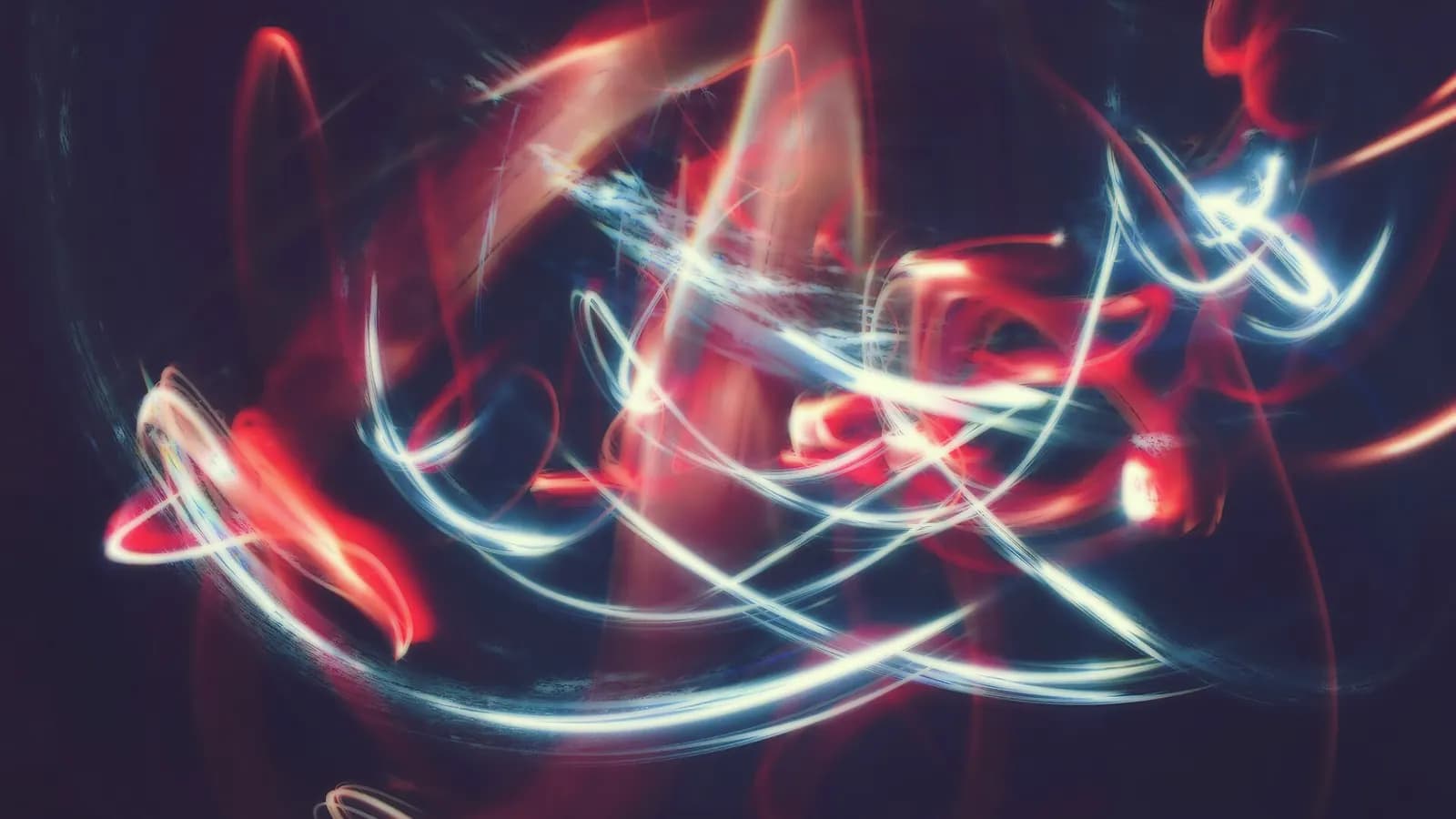 Abstract long-exposure light trails in red and blue on a dark background